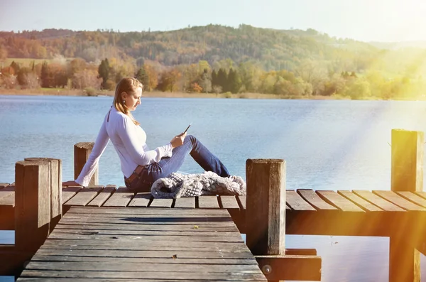 Fille lecture tablette contre lac . — Photo