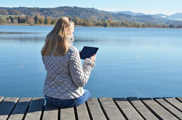Dívka čtení tablet proti jezero. — Stock fotografie