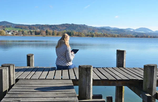 Dívka čtení tablet proti jezero. — Stock fotografie