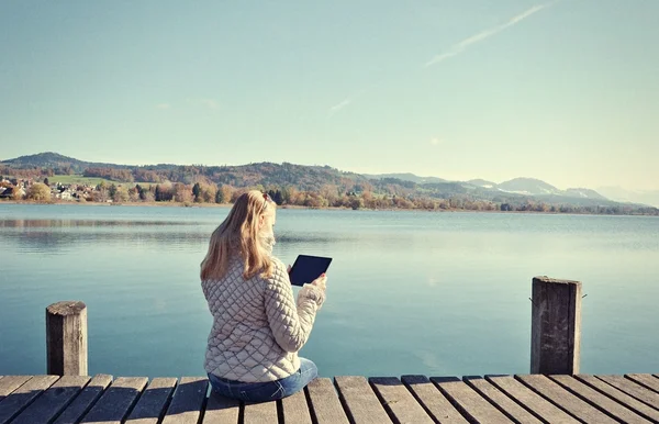 Dívka čtení tablet proti jezero. — Stock fotografie