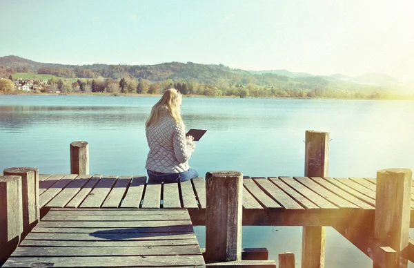 Mädchen liest Tablet gegen See — Stockfoto