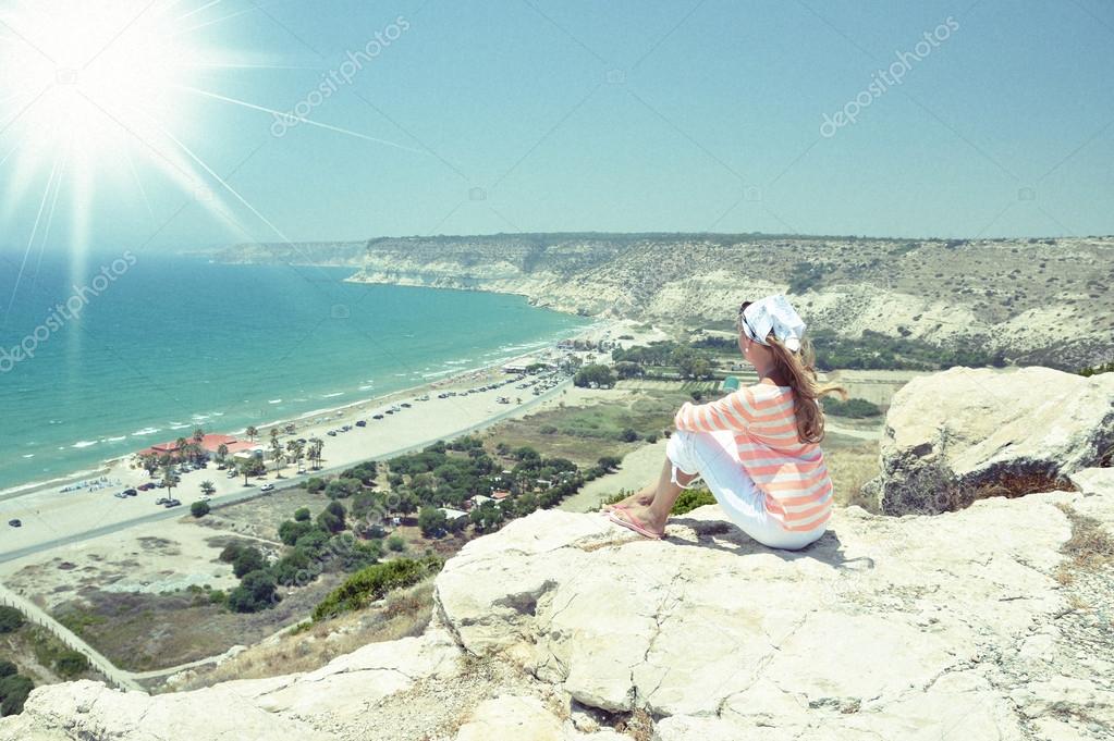 Girl on the rock looking to the ocean. Cyprus
