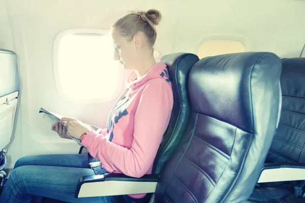 Časopis dívka čtení v letadle — Stock fotografie