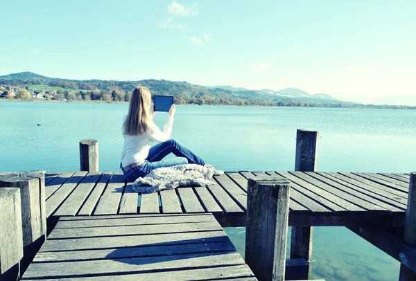 湖の近くにタブレットから読んでいる女の子. — ストック写真