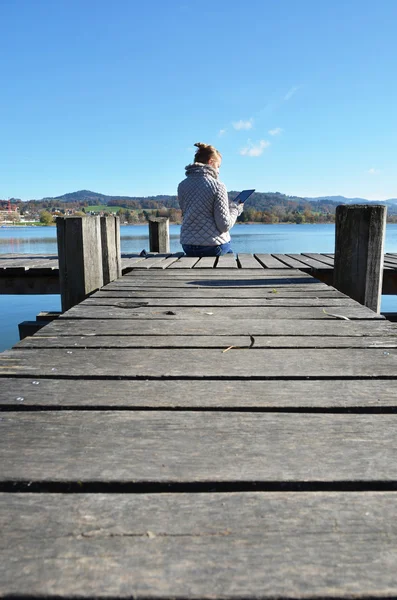 Meisje lezen van Tablet PC in de buurt van lake. — Stockfoto