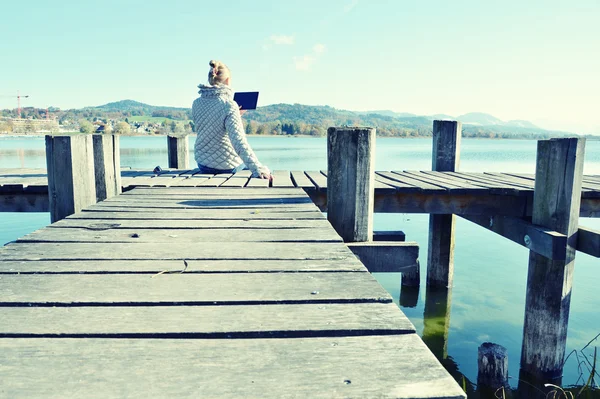 Chica leyendo desde la tableta cerca del lago . — Foto de Stock