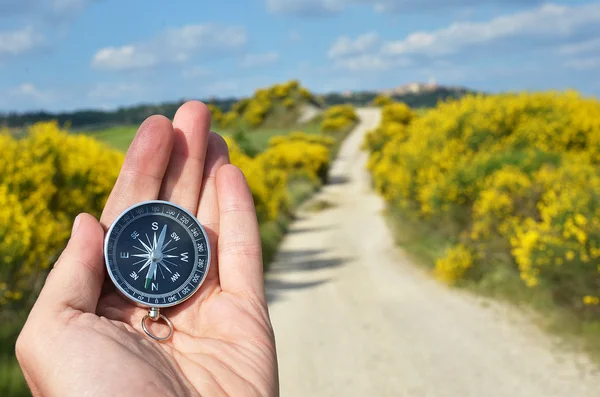 Kompass i hand mot vägen — Stockfoto