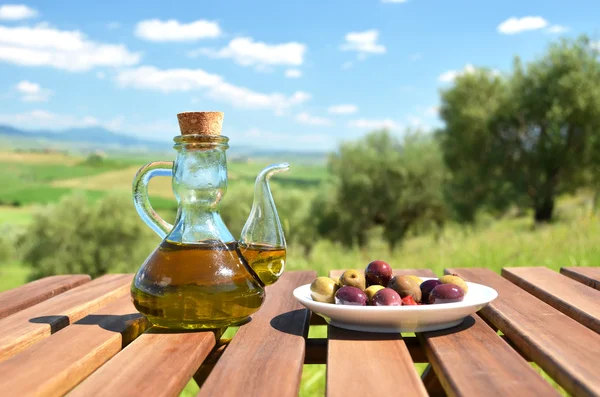 Оливковое масло и оливки против тосканского пейзажа — стоковое фото