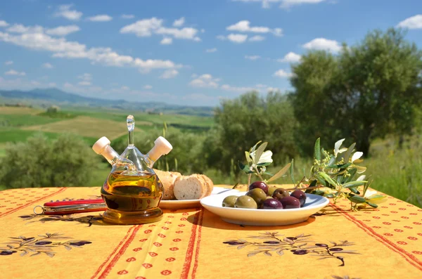 Olivenöl und Oliven gegen die toskanische Landschaft — Stockfoto