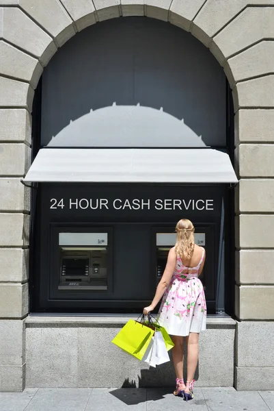 Девушка с сумками в банкомате — стоковое фото