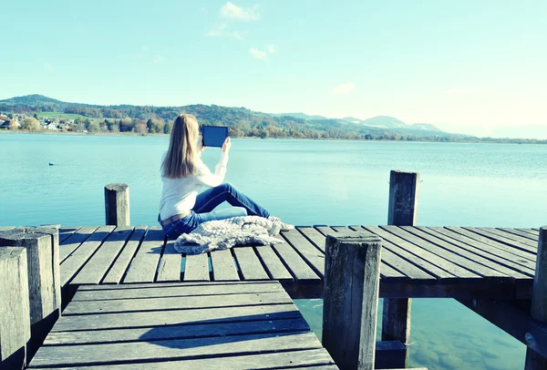 Ragazza che legge da un tablet sul molo — Foto Stock