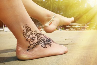 Henna tattoo on the foot on beach clipart