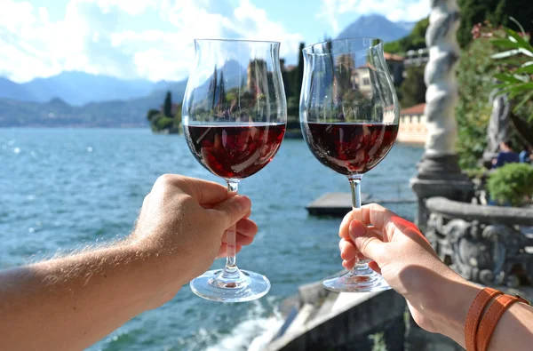 Deux verres à vin dans les mains et le lac de Côme — Photo