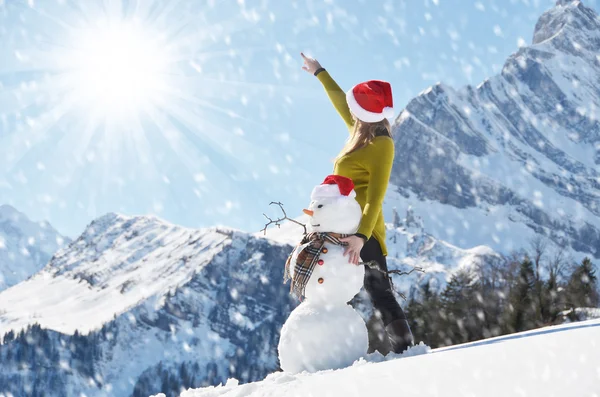 Flicka som poserar med en snögubbe — Stockfoto