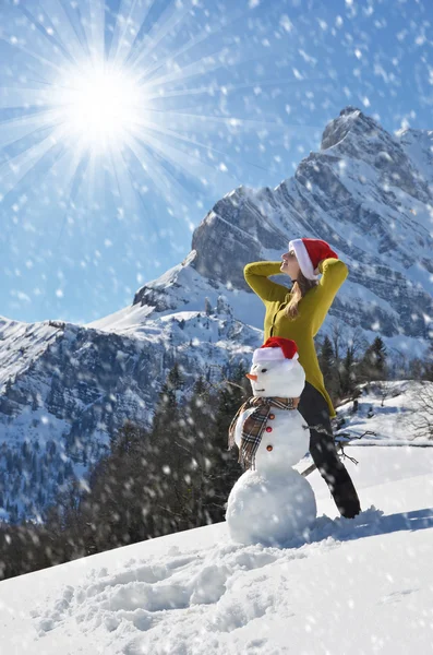 Flicka som poserar med en snögubbe — Stockfoto