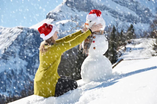 Tjej dekorera en snögubbe — Stockfoto