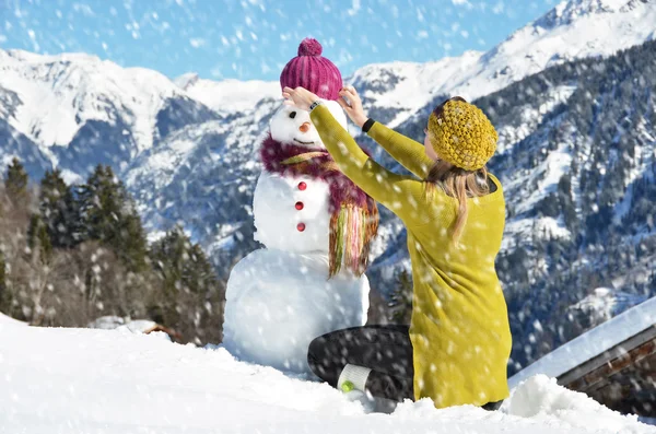 Tjej dekorera en snögubbe — Stockfoto