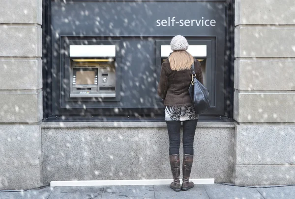 Takaisin näkymä tyttö pankkiautomaatilla — kuvapankkivalokuva