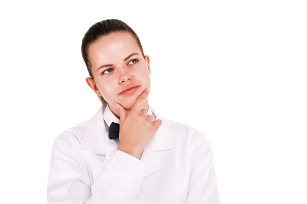 Una giovane donna in uniforme da laboratorio guarda in alto. Pensare . — Foto Stock