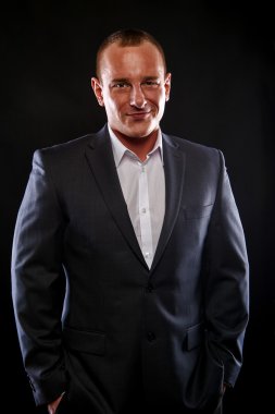 Koyu arka plan üzerinde gülümseyen takım elbiseli adam.