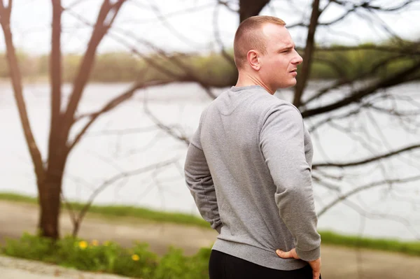 Young man resting after runing. looking on river. — Stock Photo, Image