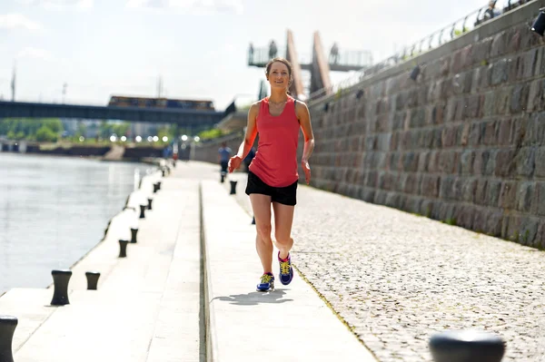 Vältränad kvinna jogging vid floden. — Stockfoto