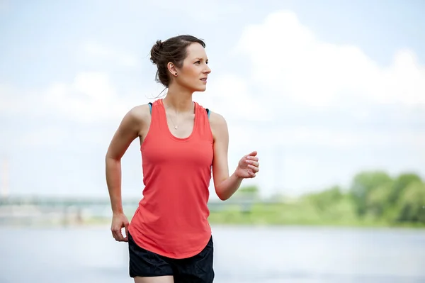 Vältränad kvinna jogging vid floden. — Stockfoto