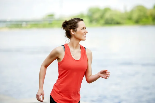 Vältränad kvinna jogging vid floden. — Stockfoto