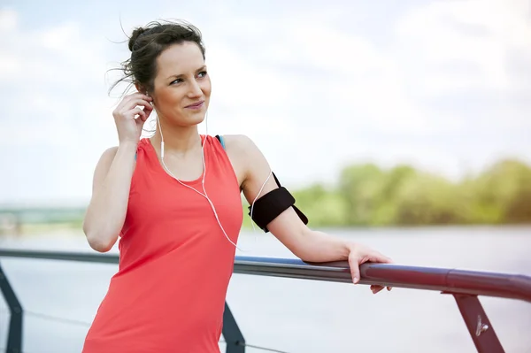 Ταιριάζει jogger γυναίκα ανάπαυση μετά τρέχω ακούγοντας μουσική. — Φωτογραφία Αρχείου