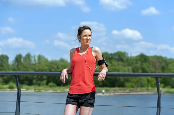 Ταιριάζει jogger γυναίκα ανάπαυση μετά τρέχω ακούγοντας μουσική. — Φωτογραφία Αρχείου