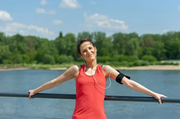 Ταιριάζει jogger γυναίκα ανάπαυση μετά τρέχω ακούγοντας μουσική. Χαμογελώντας. — Φωτογραφία Αρχείου