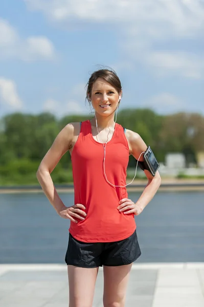 Mujer en forma jogger descansando después de correr escuchando música. Sonriendo. . — Foto de Stock