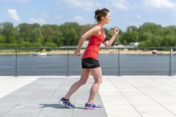 Vältränad kvinna jogging vid floden. — Stockfoto