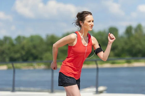 Vältränad kvinna jogging vid floden. — Stockfoto