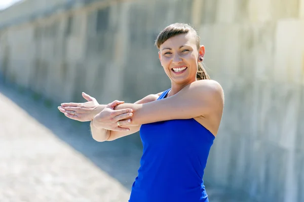 Fitnessfrau dehnt sich vor den Übungen. Lächelnd. — Stockfoto