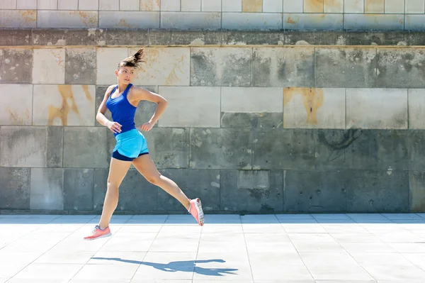 Jogger woman jump by the wall in city. look behind.