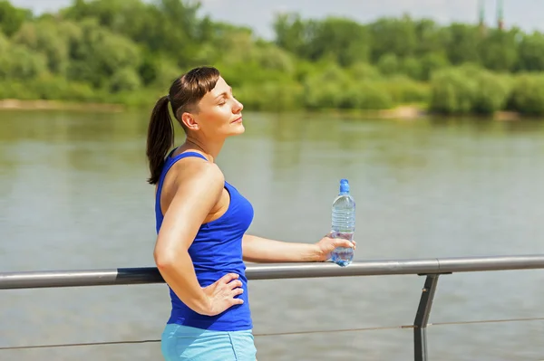 Mladé fit žena odpočívá po běhání u řeky ve městě. — Stock fotografie