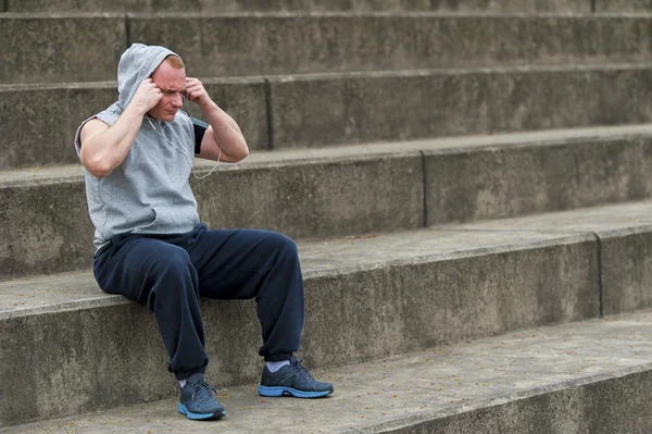 Ajuste hombre activo sentado después de ejecutar escuchar música . — Foto de Stock