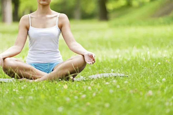 Yoga kvinnan placering på gräs meditaiting i lotusställning. — Stockfoto