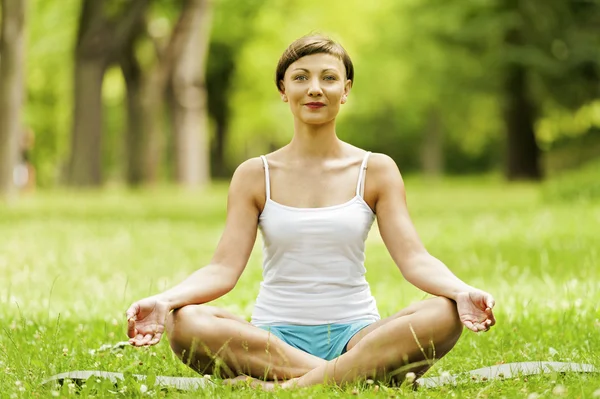 Yoga kadınla çimenlerin üzerinde siting sakin ol. — Stok fotoğraf