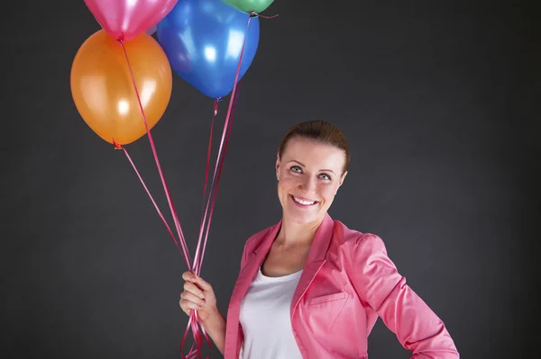 Mujer con globos sobre fondo oscuro sonriendo — Foto de Stock