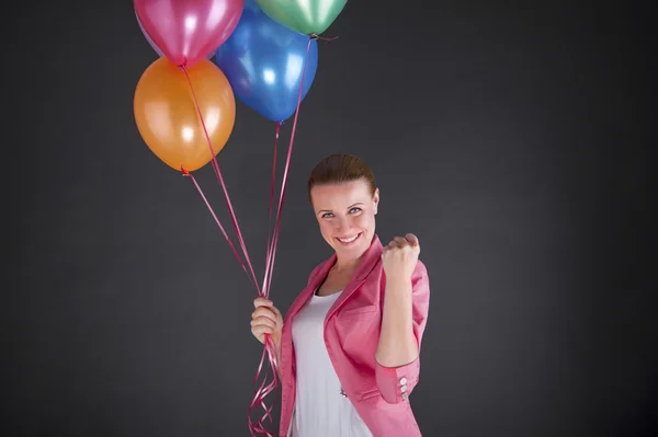 Frau mit Luftballons vor dunklem Hintergrund lächelt — Stockfoto