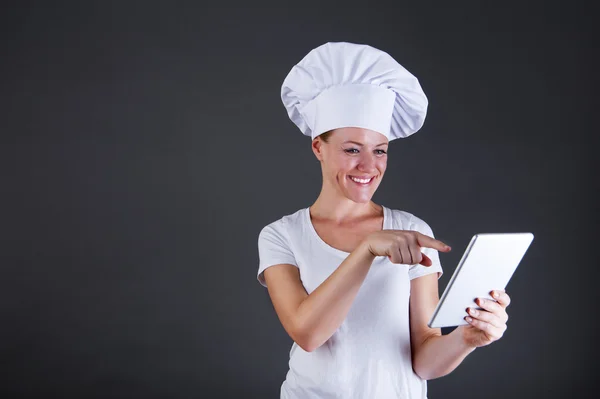 Mulher chef com tablet sobre fundo escuro — Fotografia de Stock
