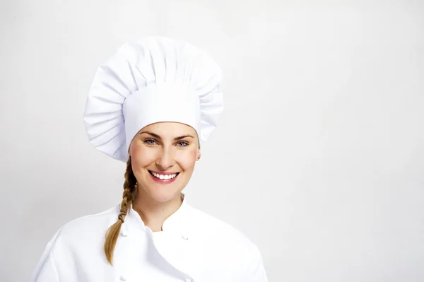 En ung, kvinnlig kock i en traditionell hatt och kappa. — Stockfoto