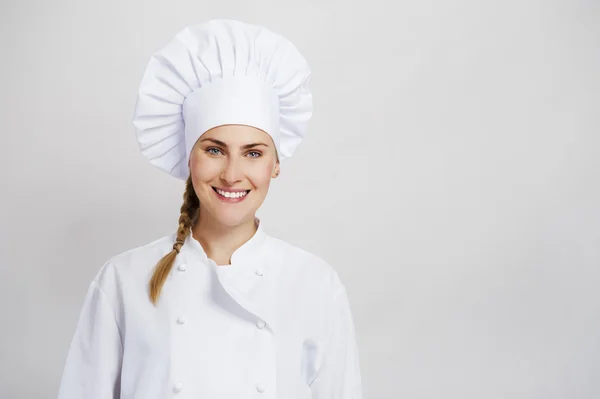 En ung, kvinnlig kock i en traditionell hatt och kappa. — Stockfoto
