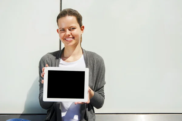 Femme tenant une tablette sur un mur de verre souriant — Photo