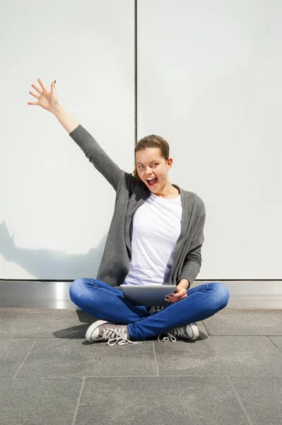 Mujer joven usando la tableta inclinada a la pared, emociones muy felices —  Fotos de Stock