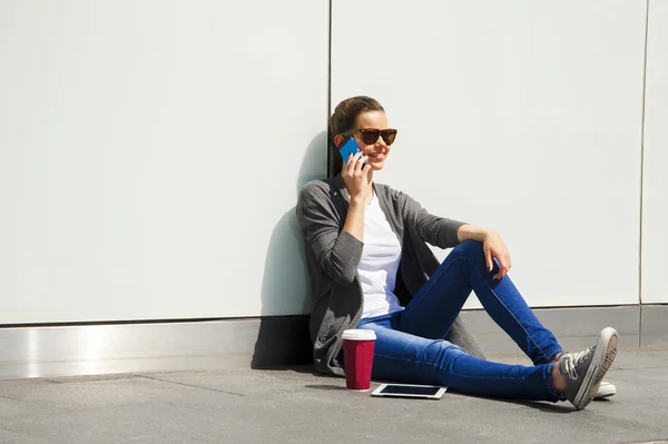 Ευτυχισμένος έφηβος κοπέλα χρησιμοποιώντας ένα έξυπνο τηλέφωνο πάνω από τον τοίχο με το backg — Φωτογραφία Αρχείου