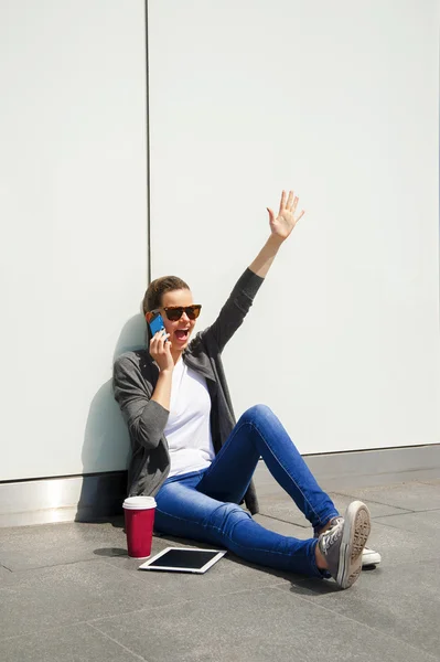 stock image Young happy teen girl using a smart phone over wall in the backg