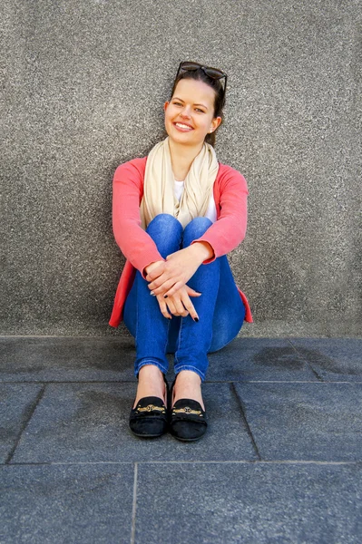 Chica por la pared en la ciudad sonriendo — Foto de Stock